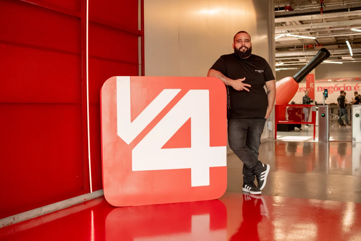 Thiago ao lado da marca V4 Company na sede da empresa